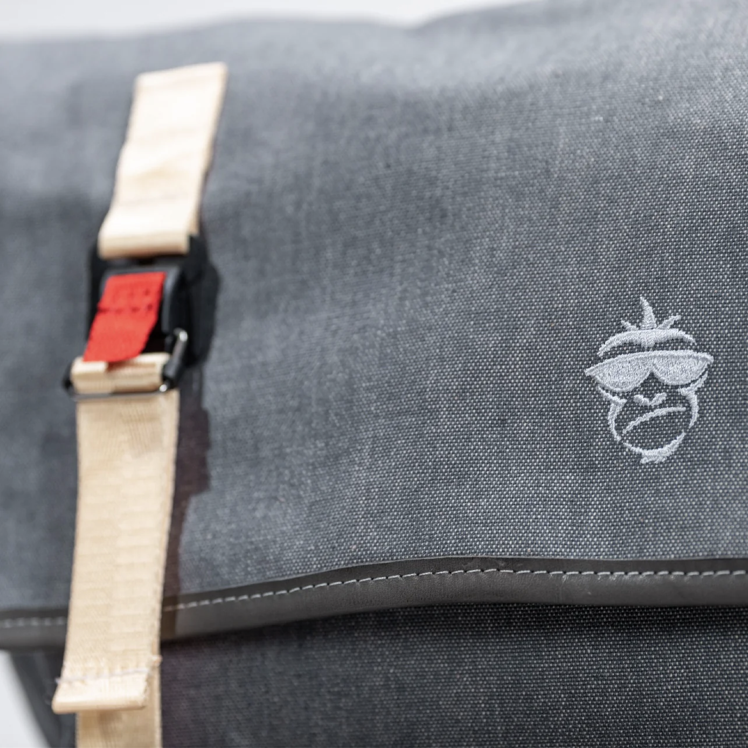 Close-up of the messenger bag's brass buckle and leather strap — durable hardware built to last