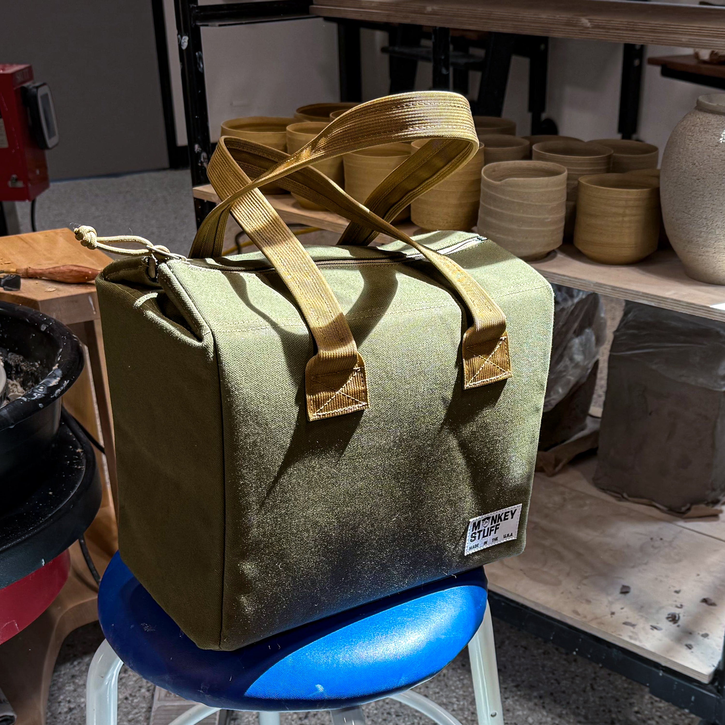 Potter carrying the Monkey Stuff bowl bag by its handle — bringing finished ceramics to a market or gallery